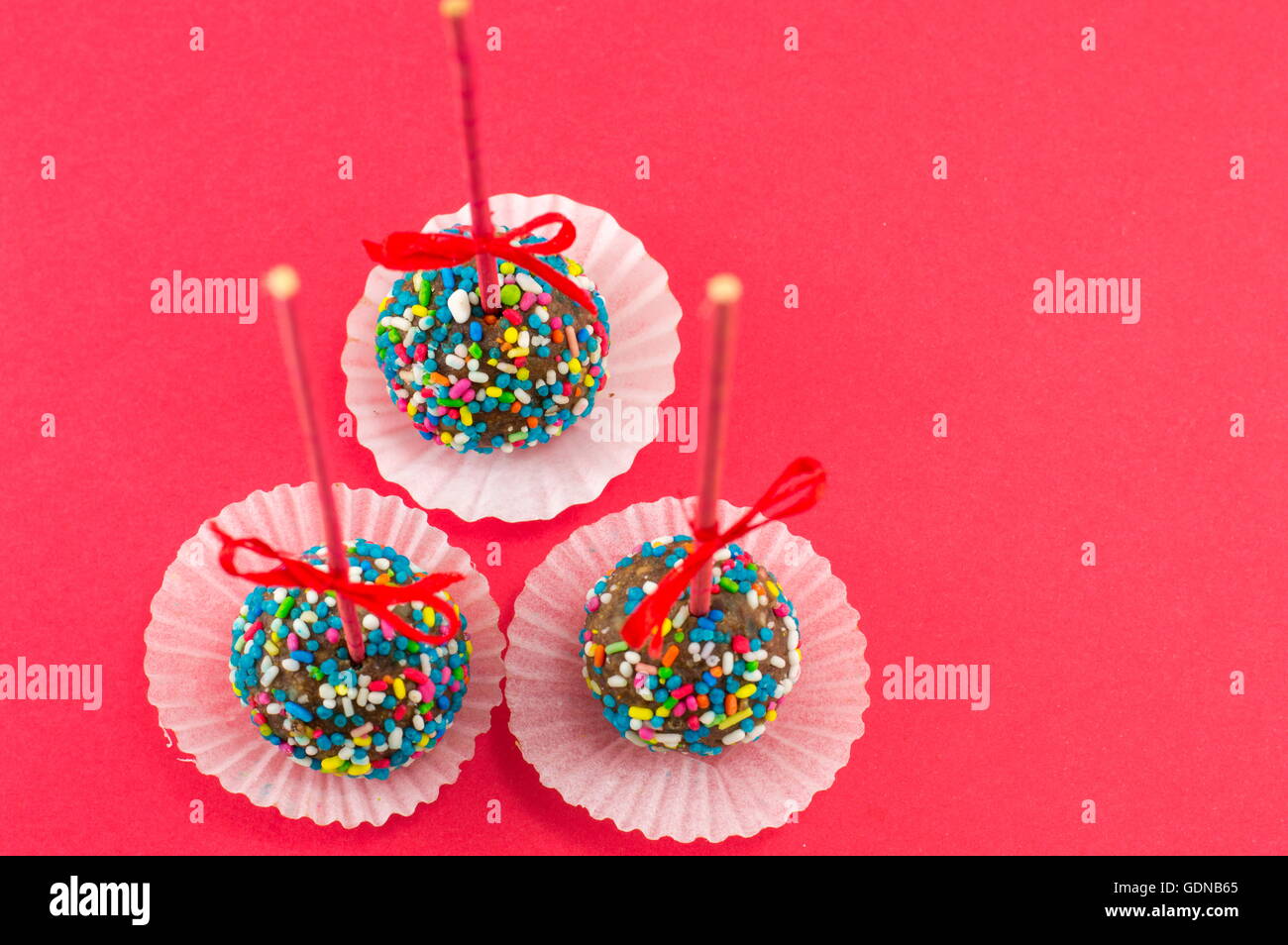 Tre cake pops su uno sfondo rosso Foto Stock