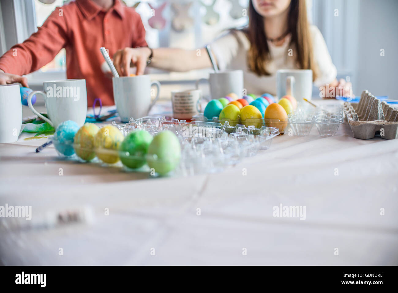 Ritagliato shot della ragazza adolescente e fratello a tavola la tintura di uova sode per la Pasqua Foto Stock