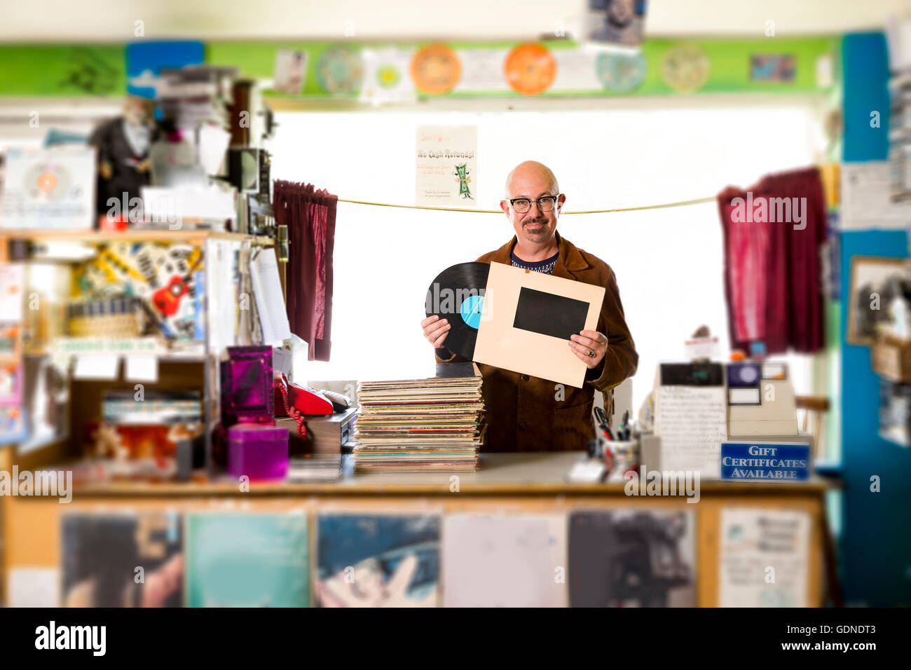 Ritratto di uomo maturo nel record shop, mettendo record nel manicotto di record Foto Stock