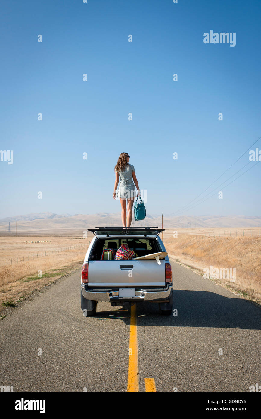 Donna in piedi sul tetto del veicolo, Highway 1, CALIFORNIA, STATI UNITI D'AMERICA Foto Stock