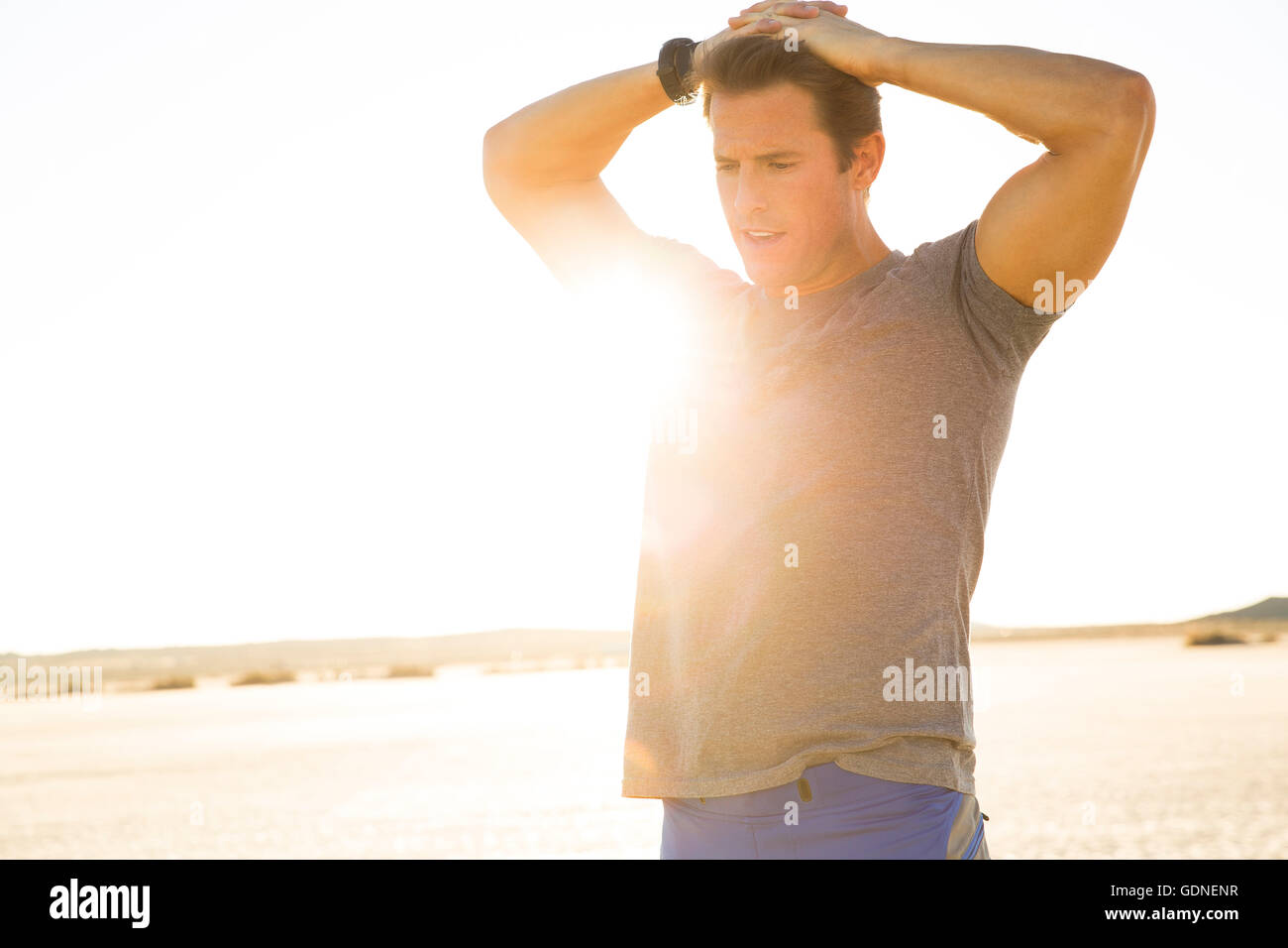 Uomo di formazione, le mani sulla testa al soleggiato dry lake bed, El Mirage, CALIFORNIA, STATI UNITI D'AMERICA Foto Stock