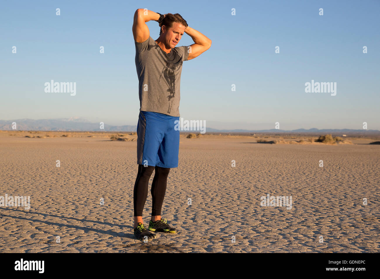Uomo di formazione, sudorazione con le mani dietro la testa sul lago secco letto, El Mirage, CALIFORNIA, STATI UNITI D'AMERICA Foto Stock