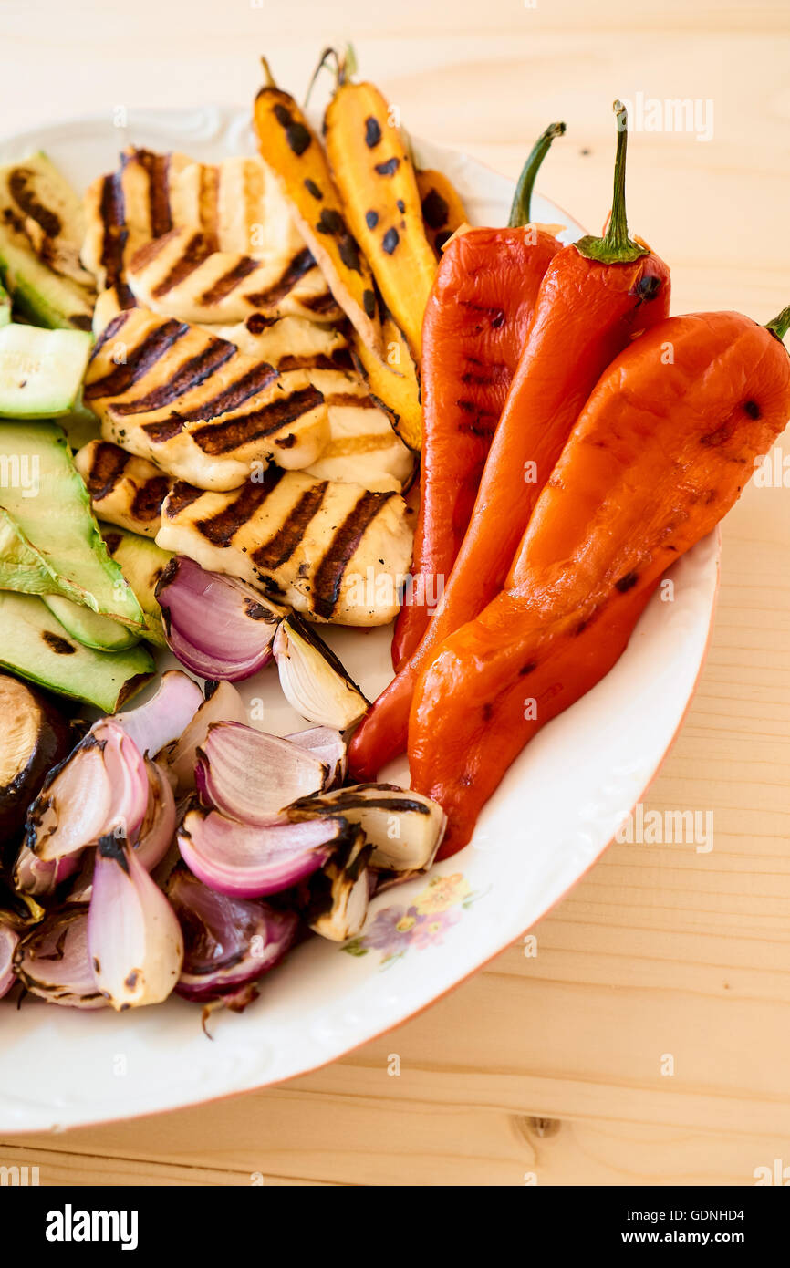 Un mix di verdure sane arrosto con halloumi cheses, su una piastra bianca, tavolo in legno, cucina dietetica Foto Stock