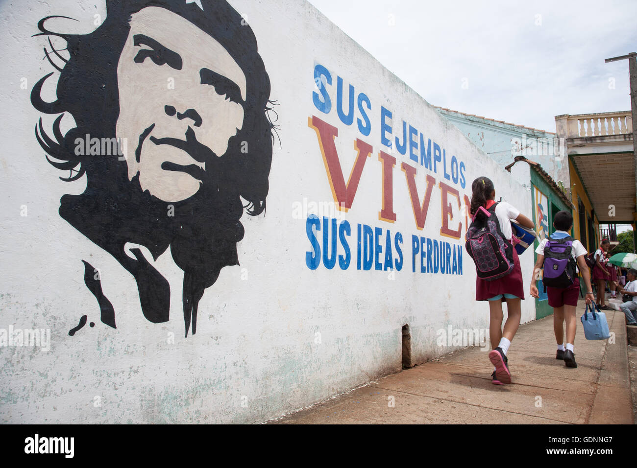 Gli scolari passano un rivoluzionario slogan e immagine del Che Gavara al di fuori della loro scuola in Baracoa, Cuba orientale Foto Stock