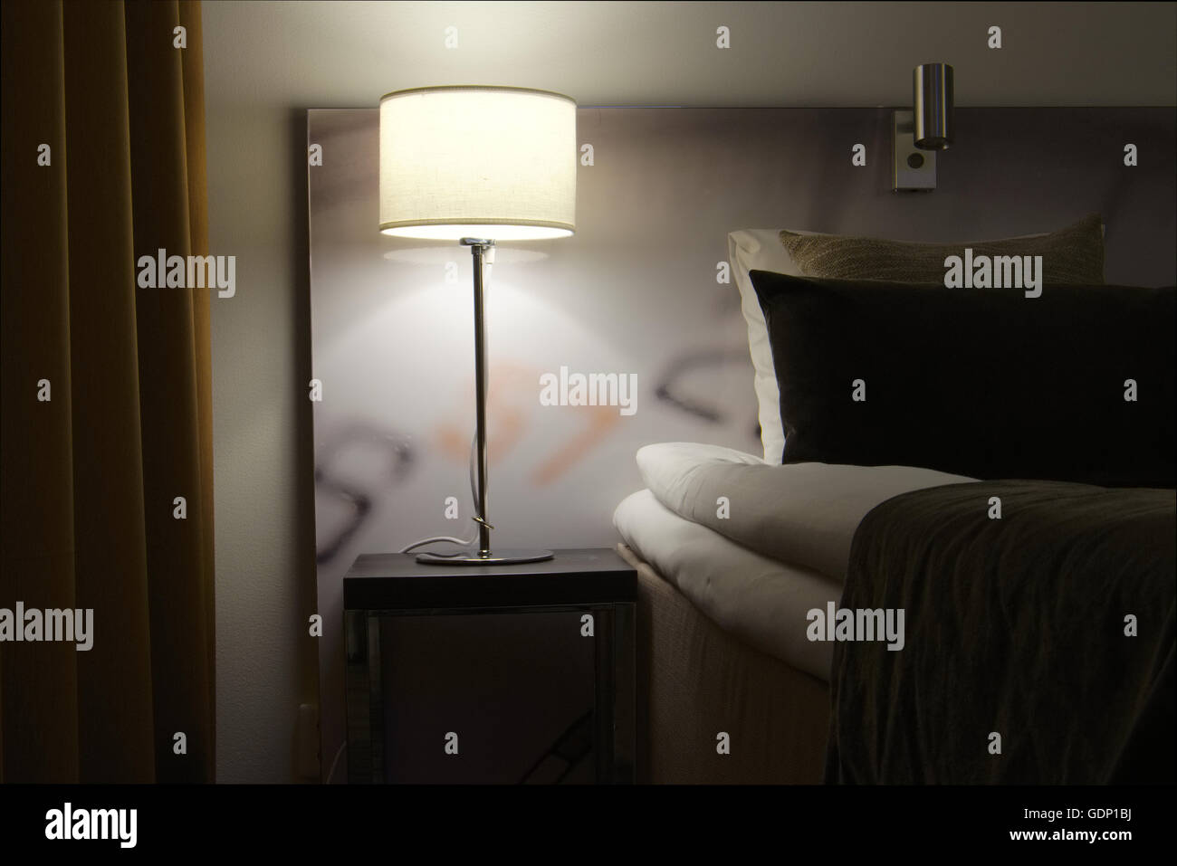 Primo piano di un letto e di notte la tabella con una lampada in piedi su di esso Foto Stock
