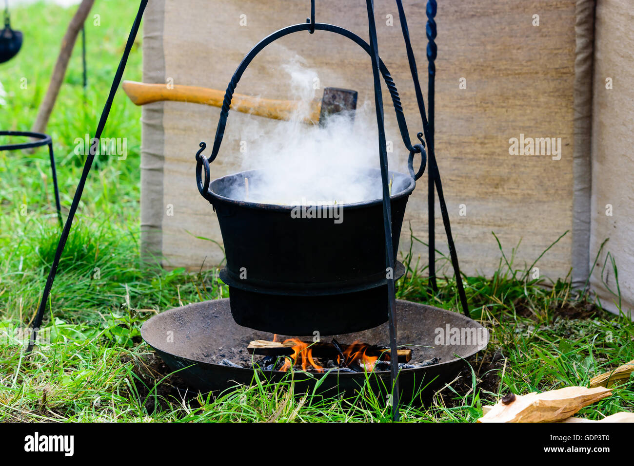 Bollente pentola di ferro appeso su un fuoco aperto. Il vapore acqueo proveniente dalla pentola. La cottura o morire in un campeggio. Foto Stock