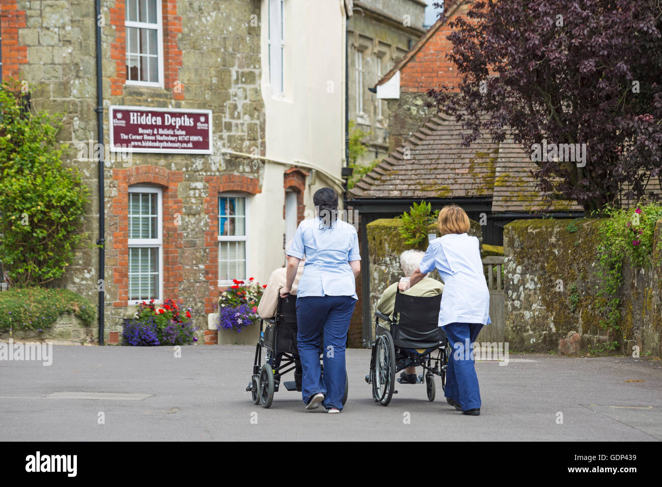 Gli anziani essendo prelevato in carrozzina a Shaftesbury, Dorset in luglio Foto Stock