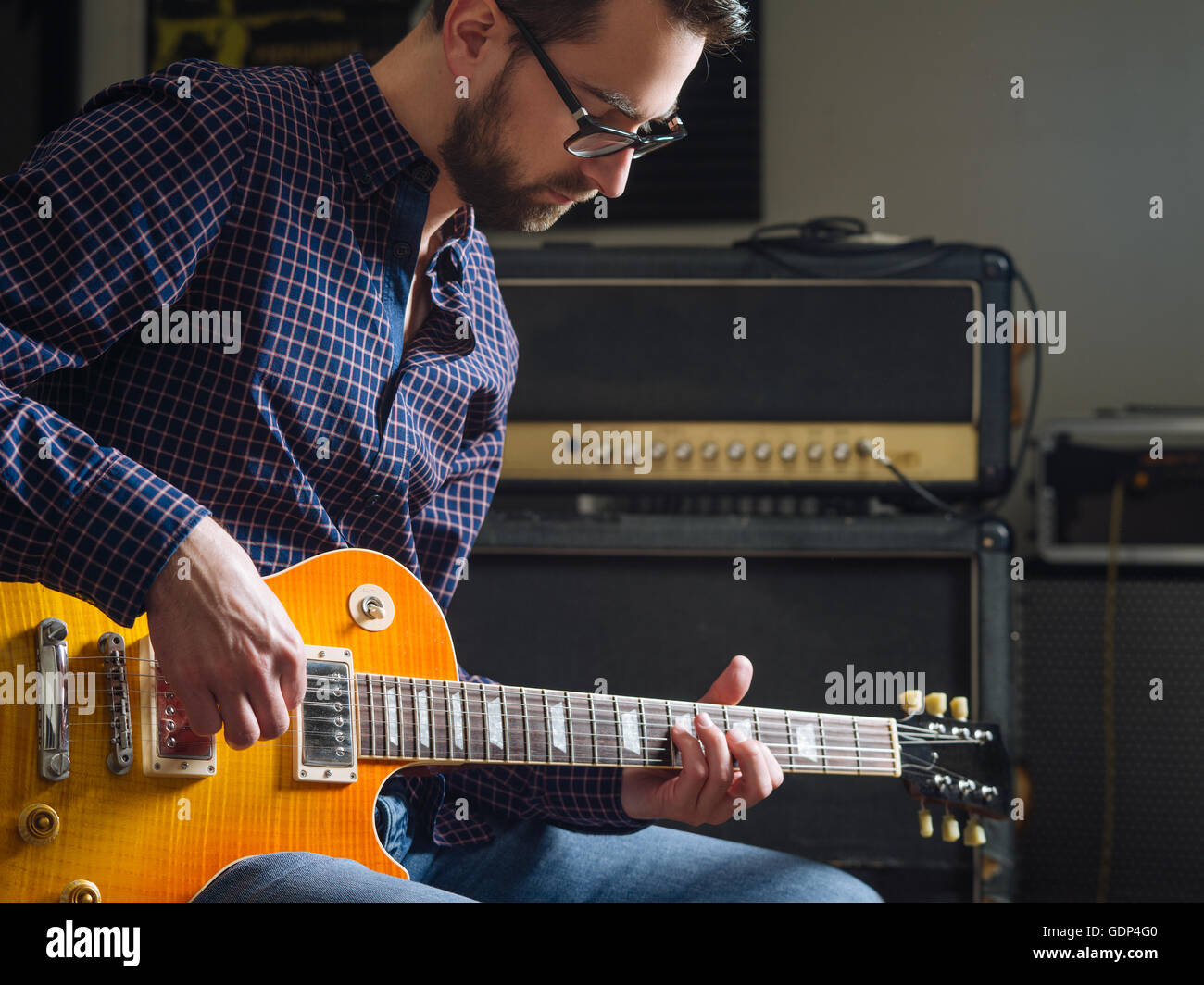 Foto di un uomo nel suo fine 20's seduti in un studio a suonare la chitarra elettrica. Foto Stock