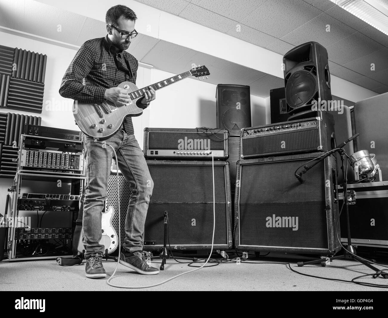 Foto di un uomo nel suo fine 20's in piedi in uno studio di registrazione a suonare la chitarra elettrica. Foto Stock