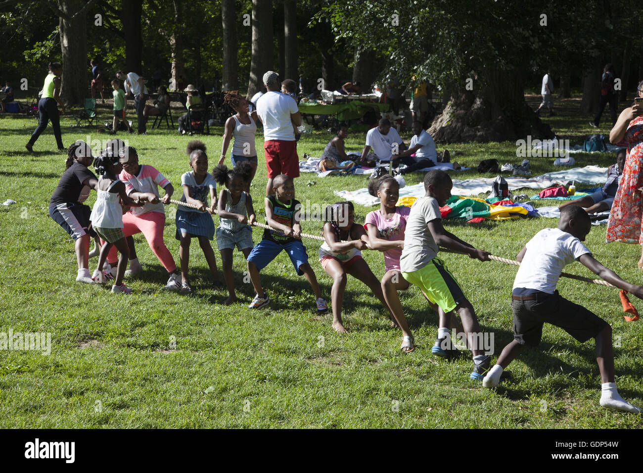 Entrambi i bambini e i genitori svolgono rimorchiatore di gioco di guerra ad un picnic in Prospect Park di Brooklyn, New York. Foto Stock