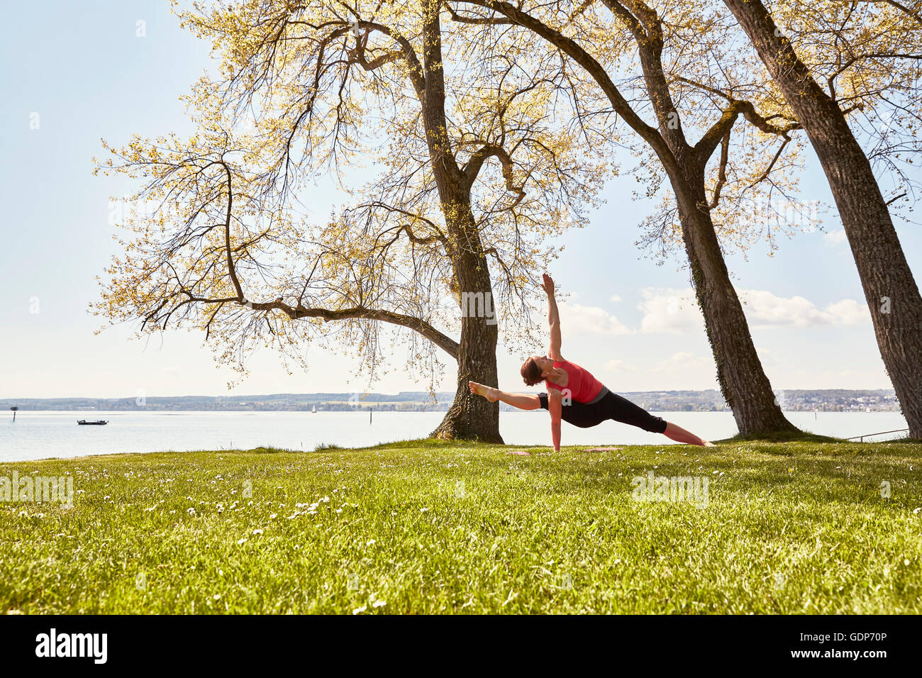 Donna con la gamba e il braccio sollevato in posizione di yoga Foto Stock