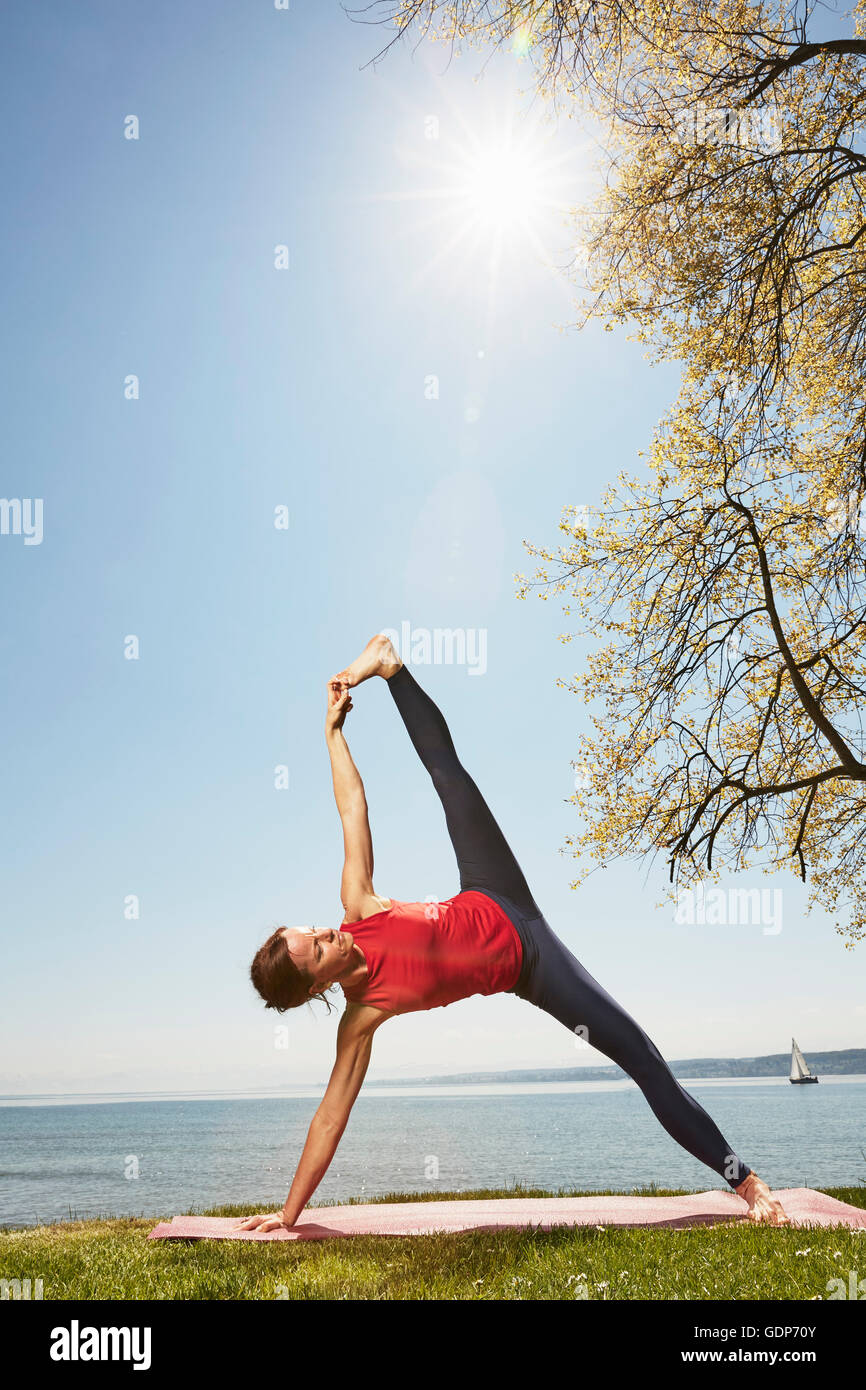 Donna con la gamba e il braccio sollevato in posizione di yoga Foto Stock