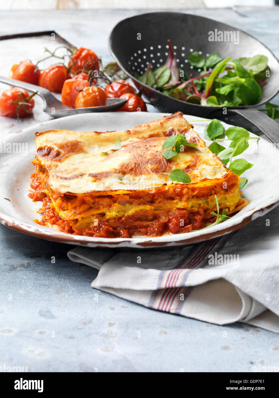 Cibo, pasti vegetariani, arrosti di zucca lasagne, formaggio, pomodori, insalata, piastra vintage, rustico scolapasta di metallo Foto Stock