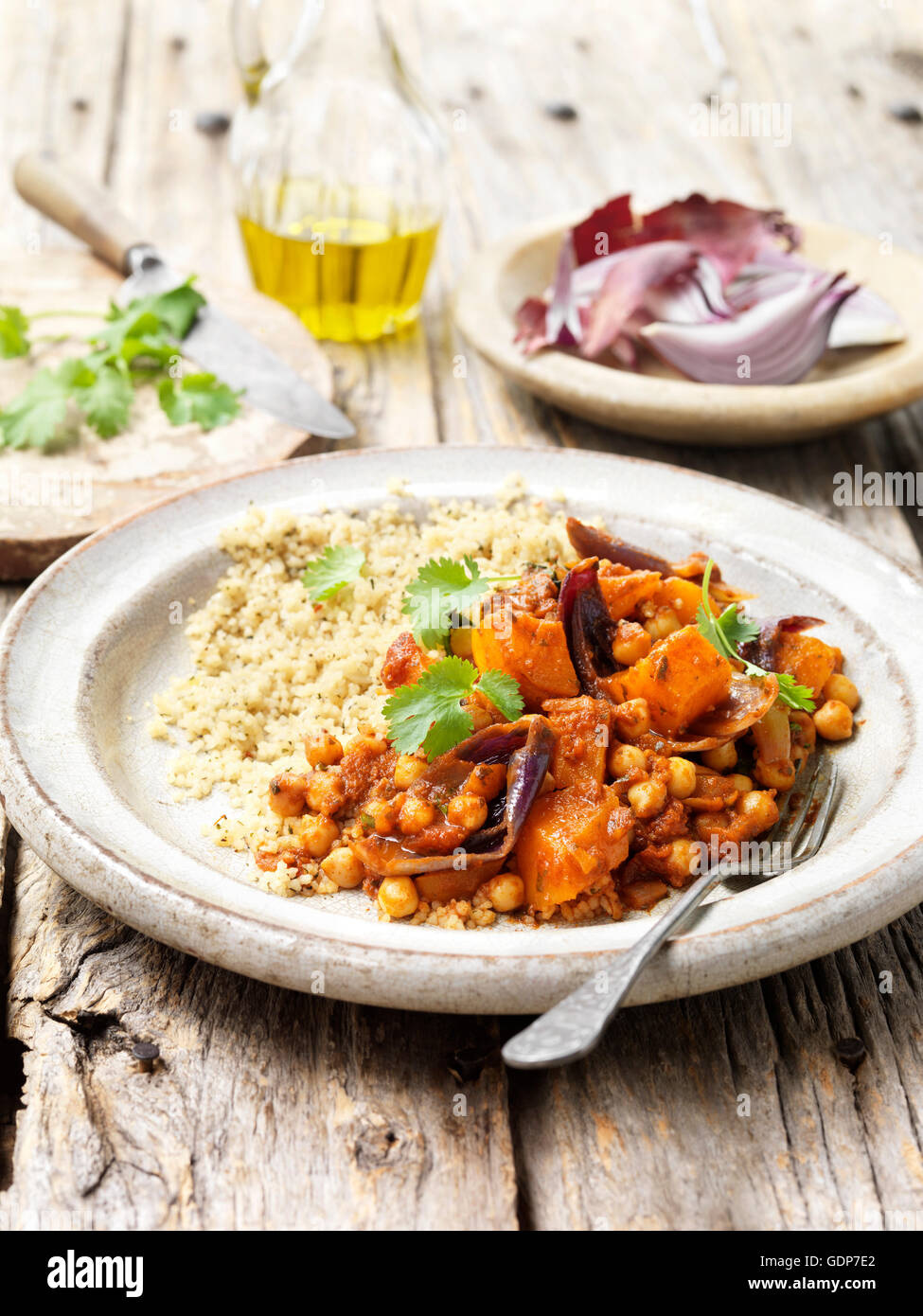 Cibo pietanze vegetariane arrosto di zucca cipolla rossa ceci cous cous di coriandolo olio di oliva tavola in legno rustico Foto Stock