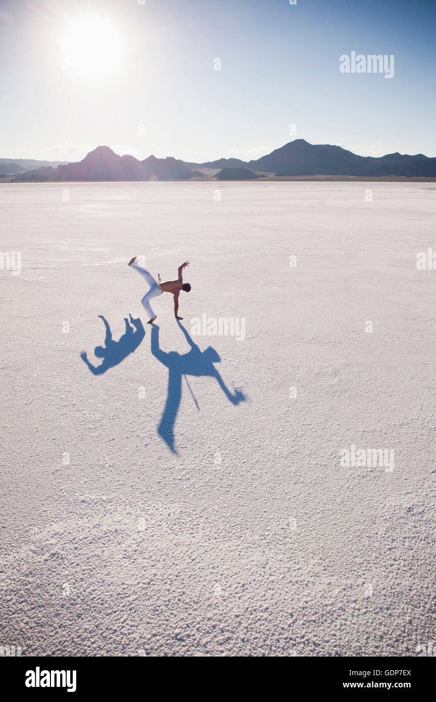 Uomo con due ombre di eseguire la capoeira su Bonneville Saline, Utah, Stati Uniti d'America Foto Stock