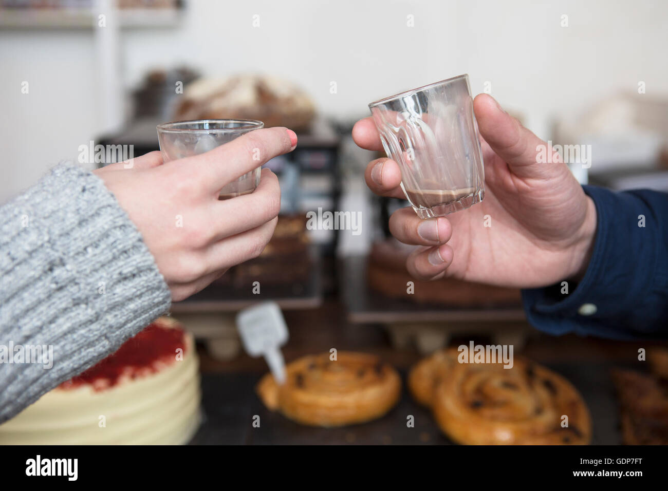 Chiusura del giovane con le mani in mano sollevando un espresso toast in cafe Foto Stock