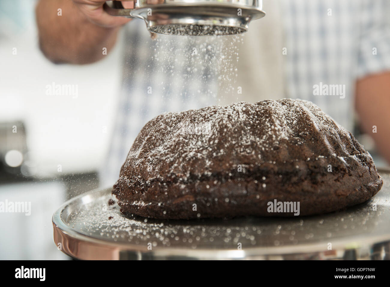 Uomo di setacciatura dello zucchero a velo sulla torta Foto Stock