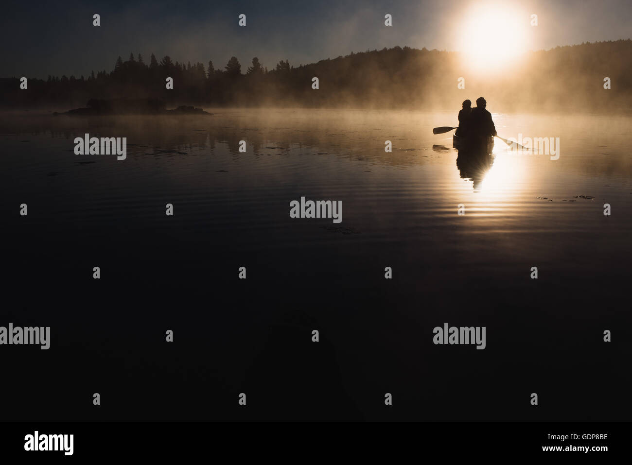 Coppia senior in canoa sul lago al tramonto Foto Stock