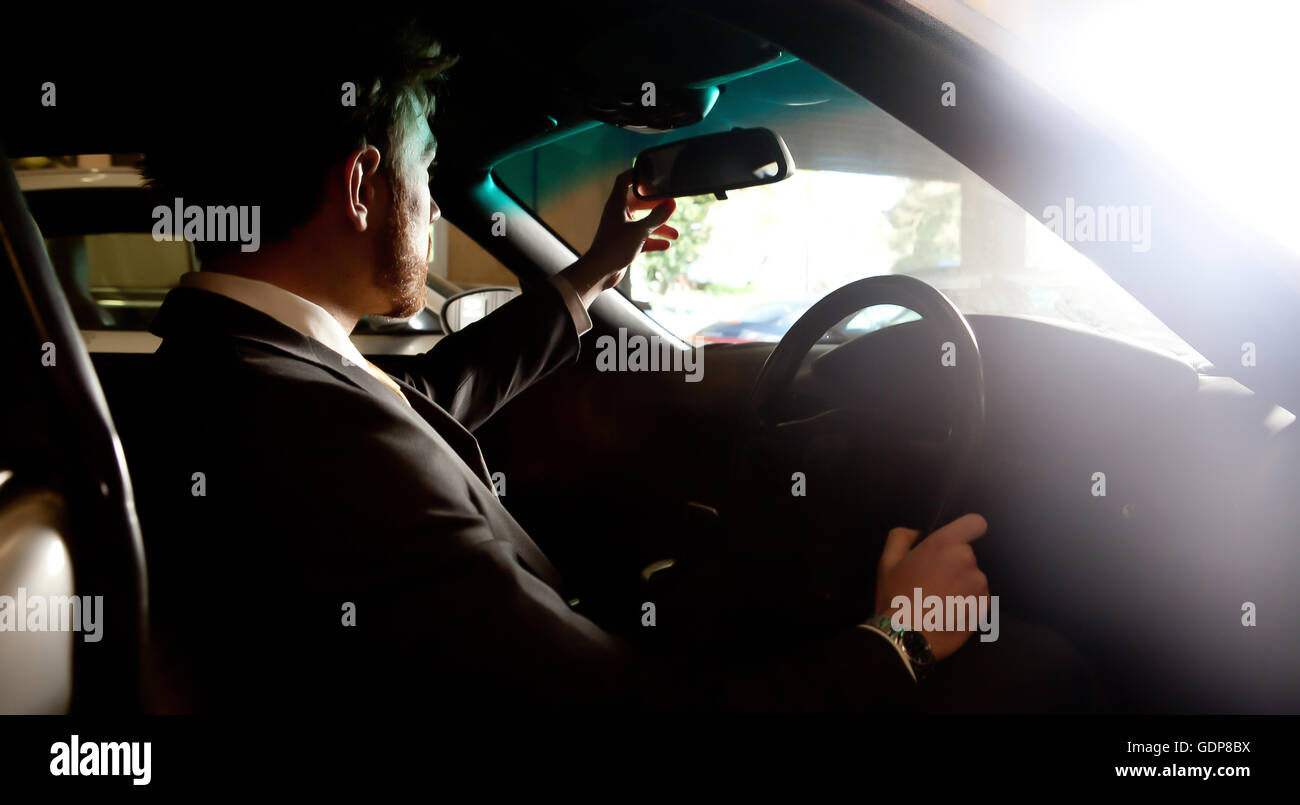 Uomo in auto, regolazione specchietto retrovisore Foto Stock