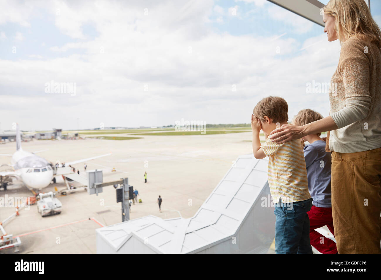Madre e figli guardando fuori della finestra di airport Foto Stock