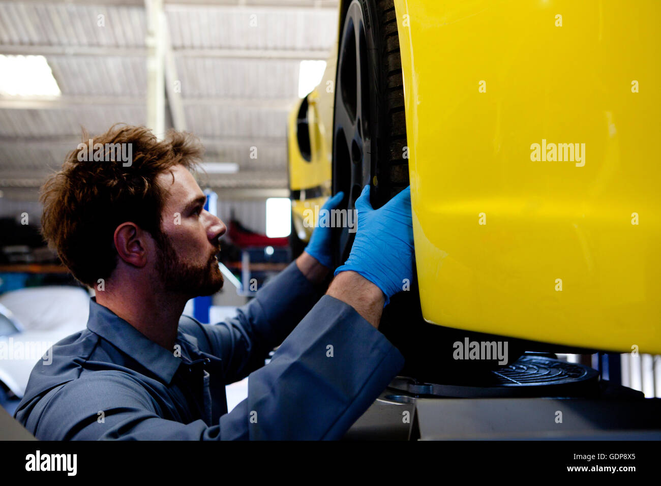 Maschio di allineamento meccanico ruota sul giallo auto sportiva Foto Stock