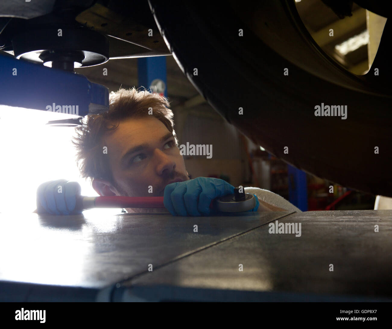 Meccanico maschio guardando il parallelismo su auto sportiva Foto Stock