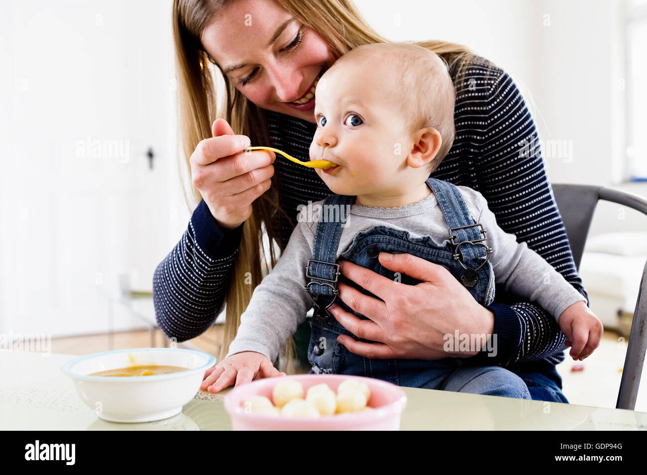 Alimentazione donna bambina a tavola Foto Stock