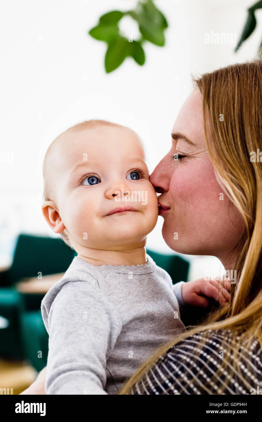 Donna bambino portando la figlia e la bacia la guancia Foto Stock