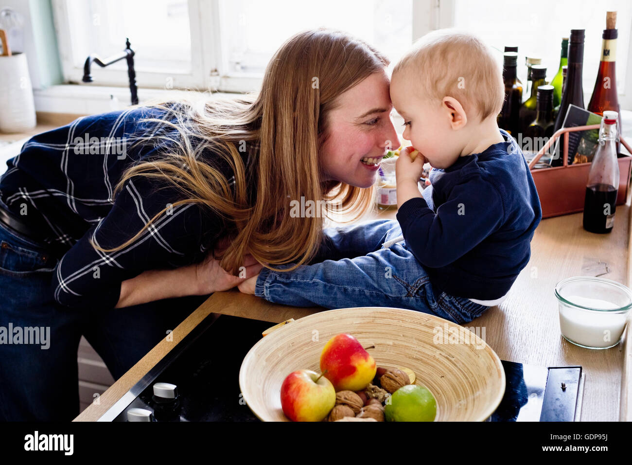 Donna che gioca con il bambino figlio sul banco di cucina Foto Stock