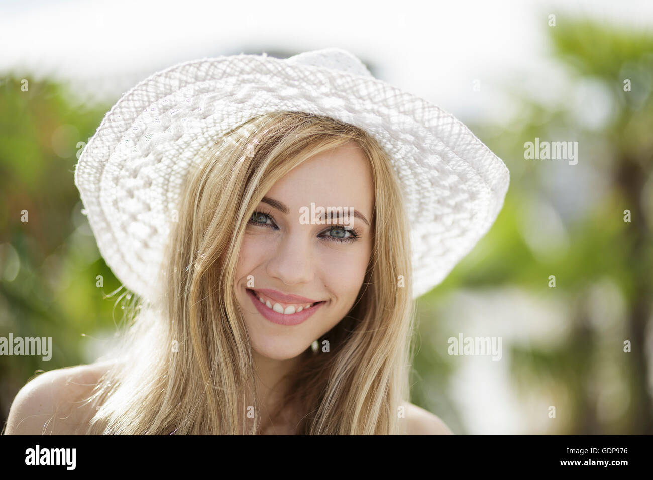Ritratto della bella ragazza bionda che indossa cappello di paglia in città Foto Stock
