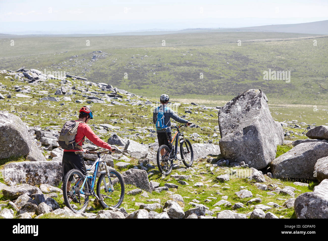 Vista posteriore dei ciclisti di biciclette a piedi giù collina rocciosa Foto Stock