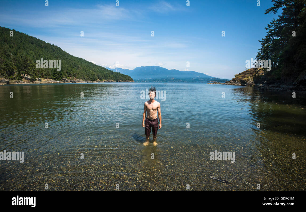 Uomo in mare gettando i capelli umidi indietro, Bowen Island, British Columbia, Canada Foto Stock