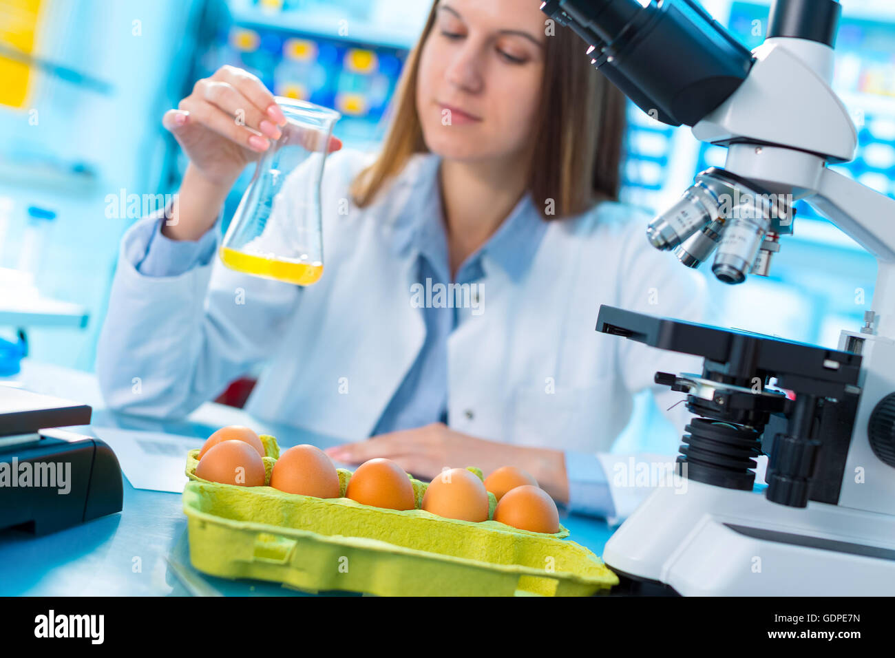 Ragazza nel test di laboratorio di qualità alimentare uovo. Verificare che il contenuto di proteine, grassi, colesterolo e agenti patogeni Foto Stock