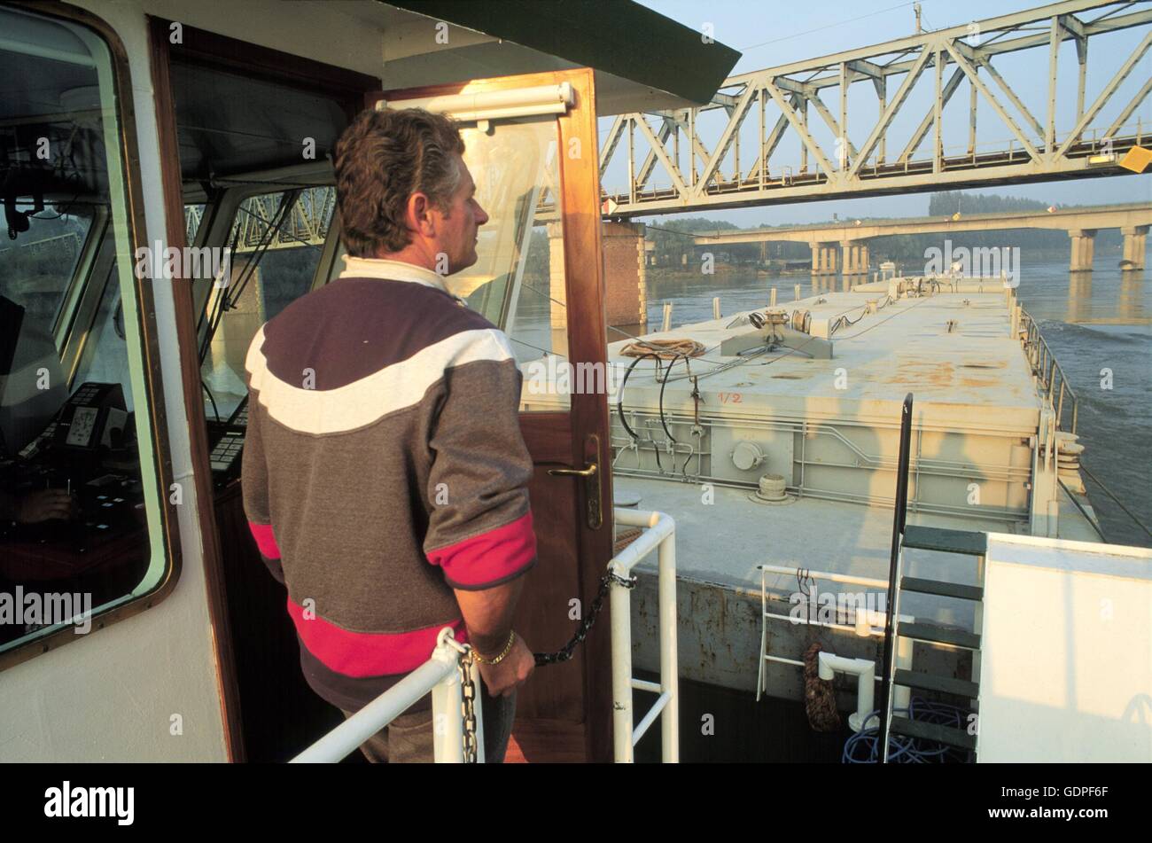 Spintore la barca con una chiatta per il trasporto di merci in navigazione sul fiume Po (Italia) Foto Stock