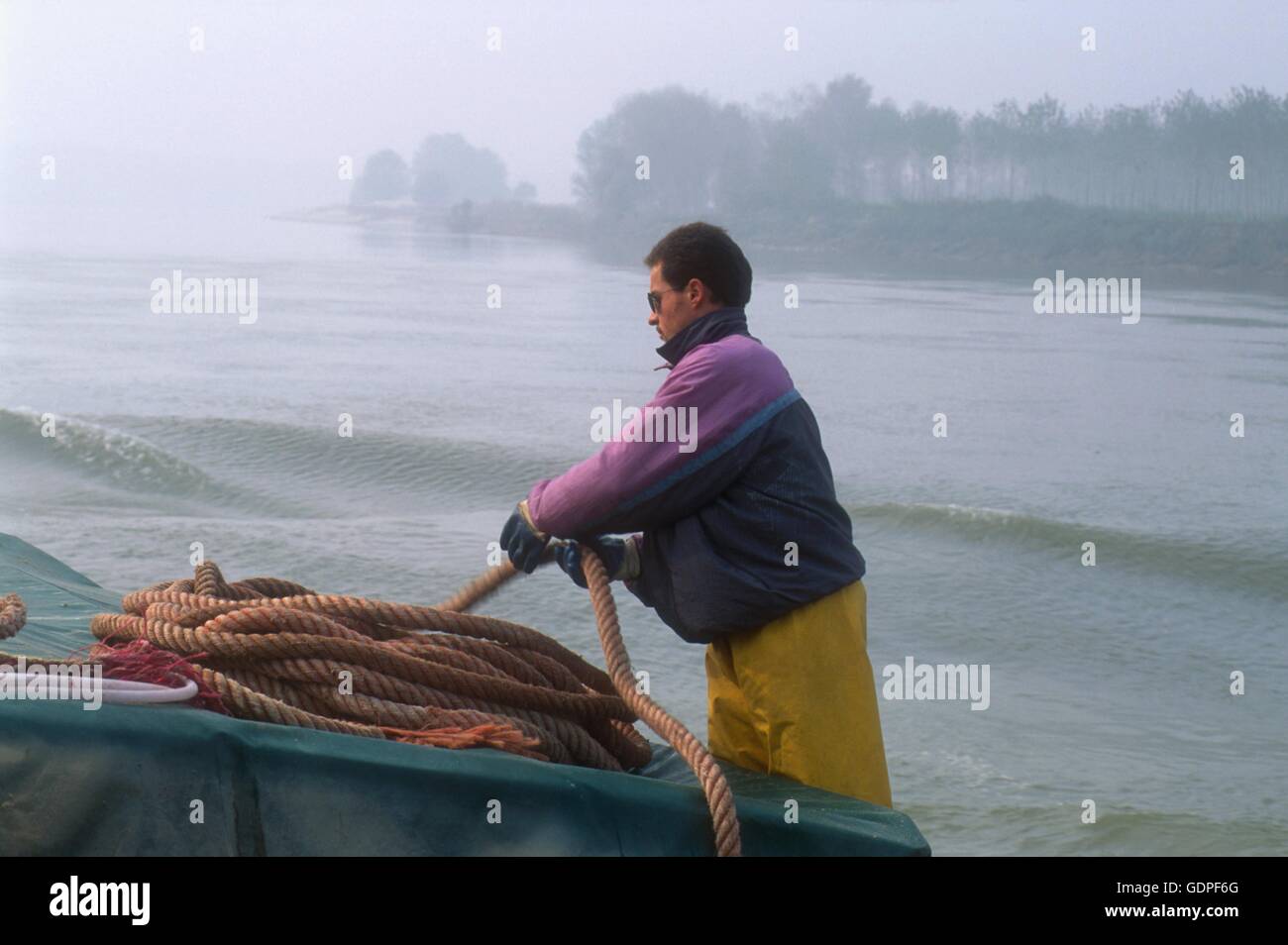 Spintore la barca con una chiatta per il trasporto di merci in navigazione sul fiume Po (Italia) Foto Stock