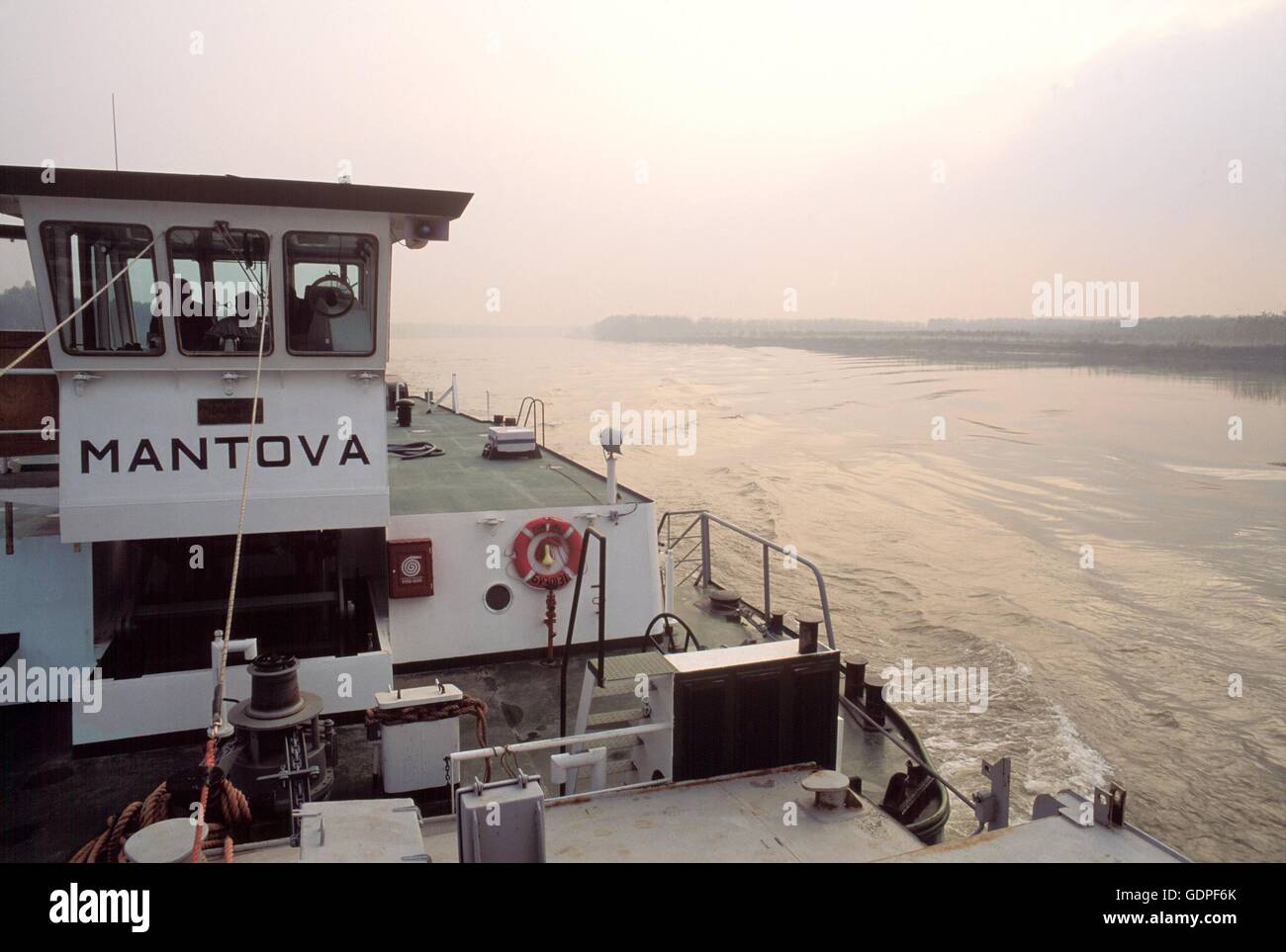 Spintore la barca con una chiatta per il trasporto di merci in navigazione sul fiume Po (Italia) Foto Stock