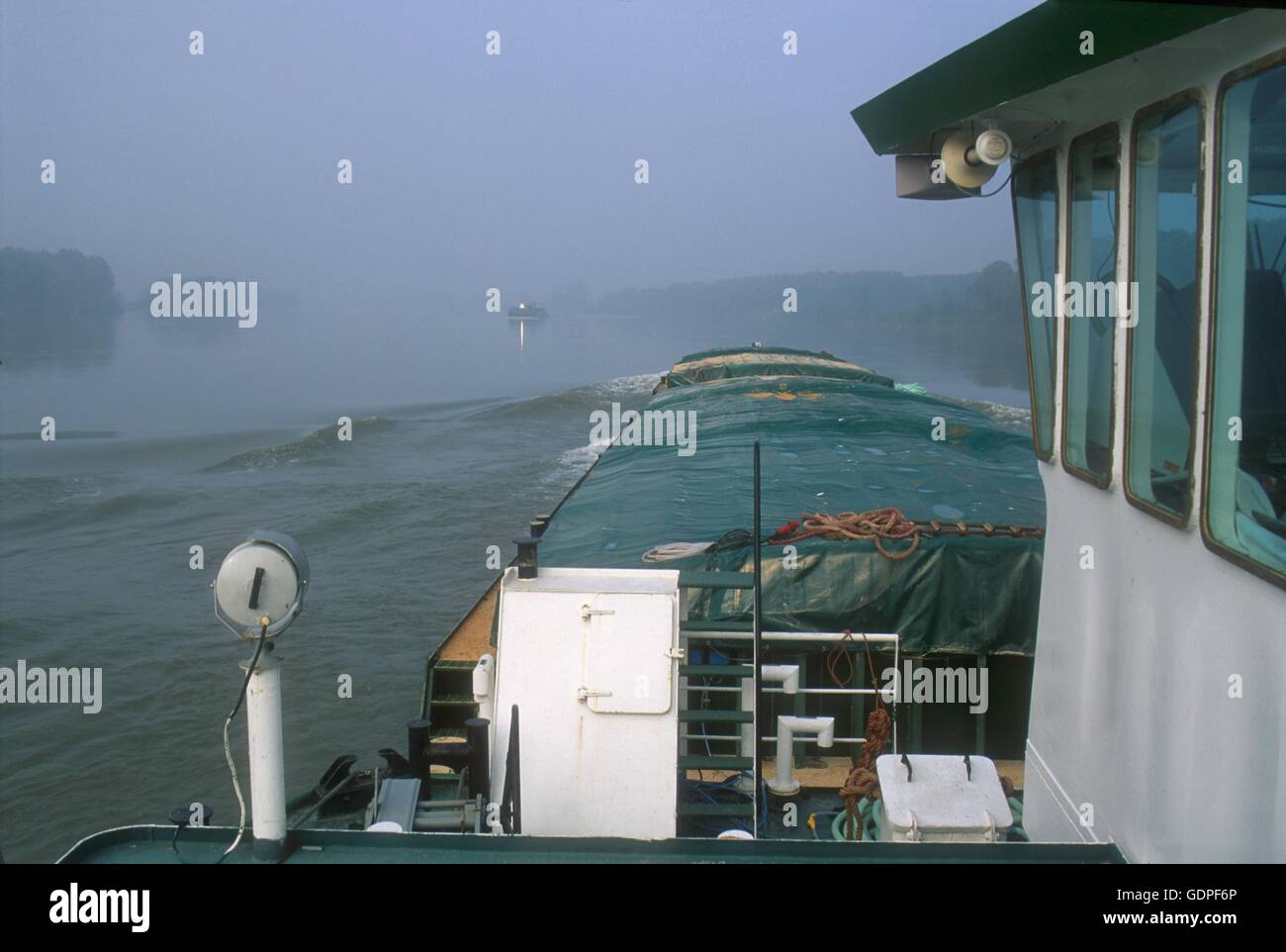Spintore la barca con una chiatta per il trasporto di merci in navigazione sul fiume Po (Italia) Foto Stock