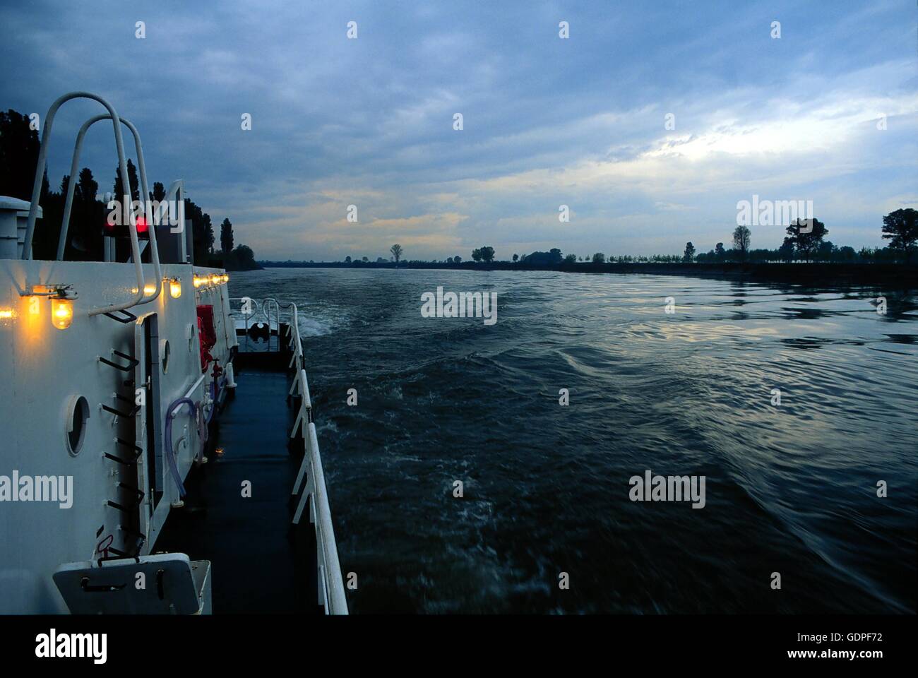 Spintore la barca con una chiatta per il trasporto di merci in navigazione sul fiume Po (Italia) Foto Stock