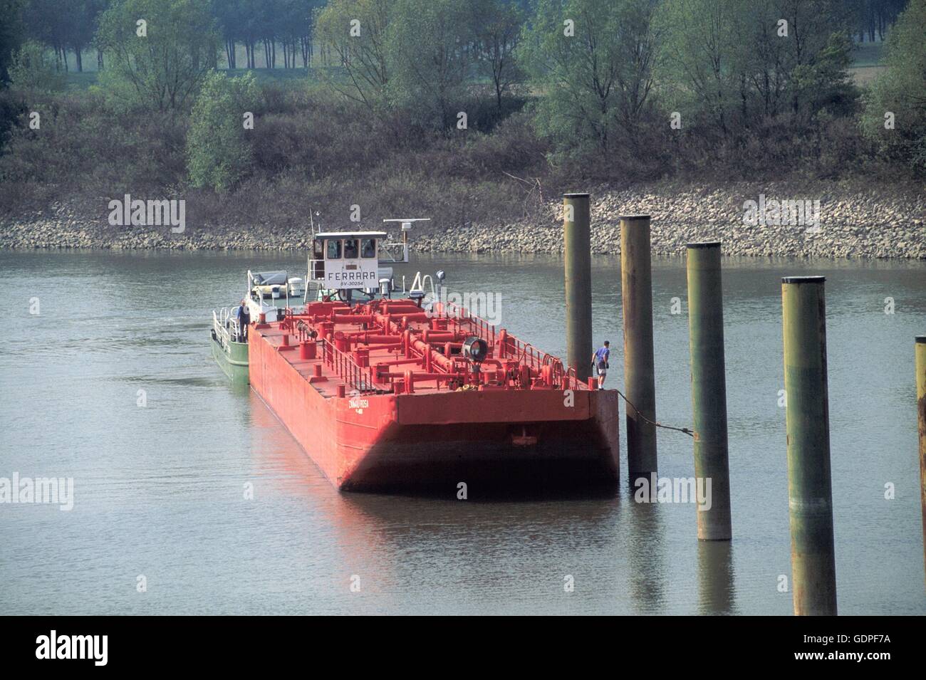 Spintore la barca con una chiatta per il trasporto di merci in navigazione sul fiume Po (Italia) Foto Stock