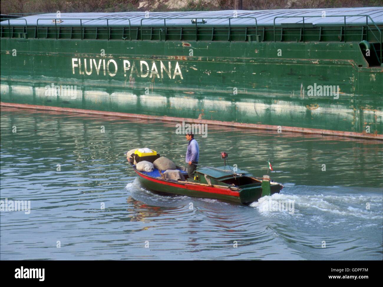 Spintore la barca con una chiatta per il trasporto di merci in navigazione sul fiume Po (Italia) Foto Stock