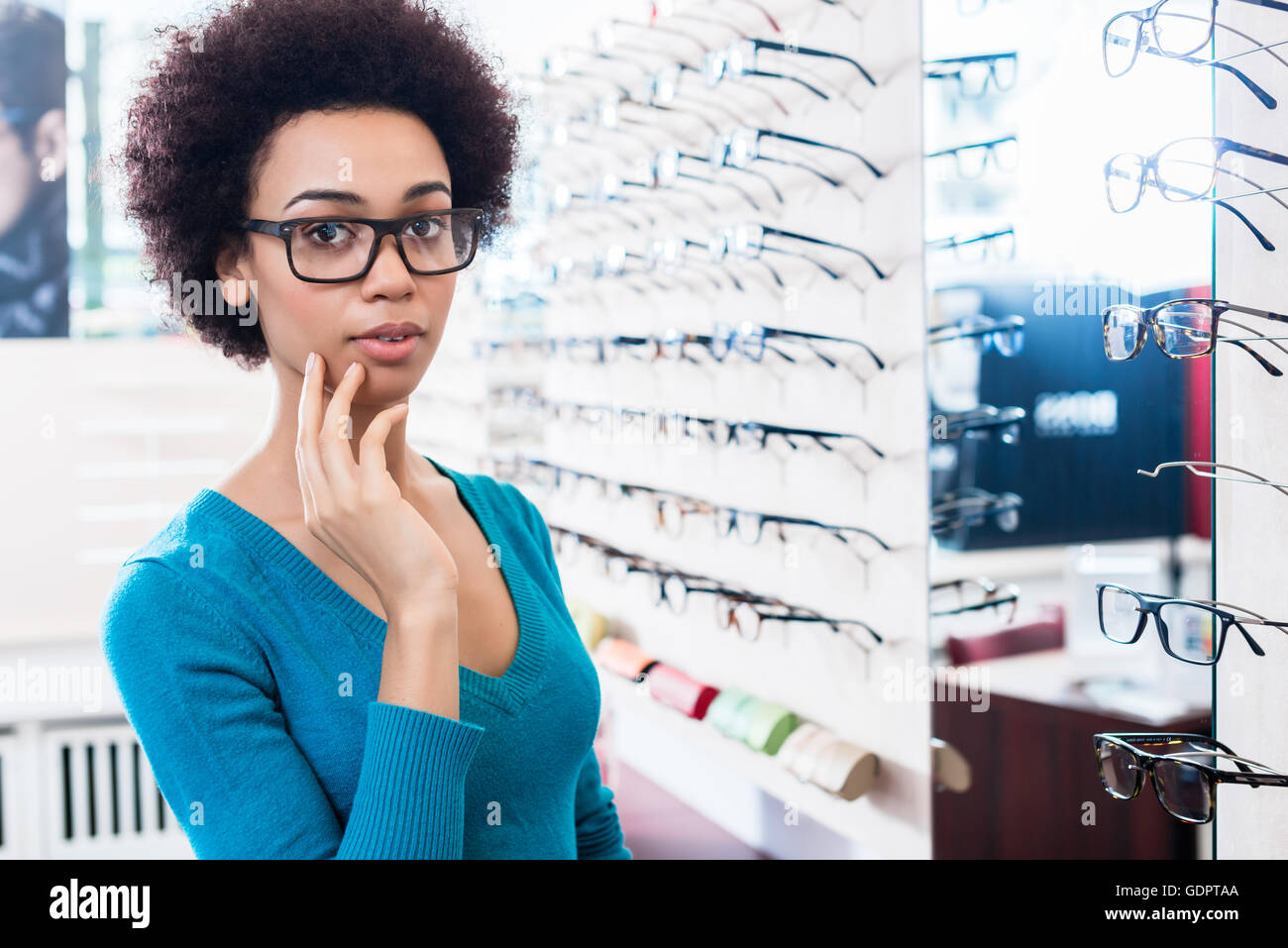 Nero donna cercando sui bicchieri che vuole acquistare in negozio ottico Foto Stock