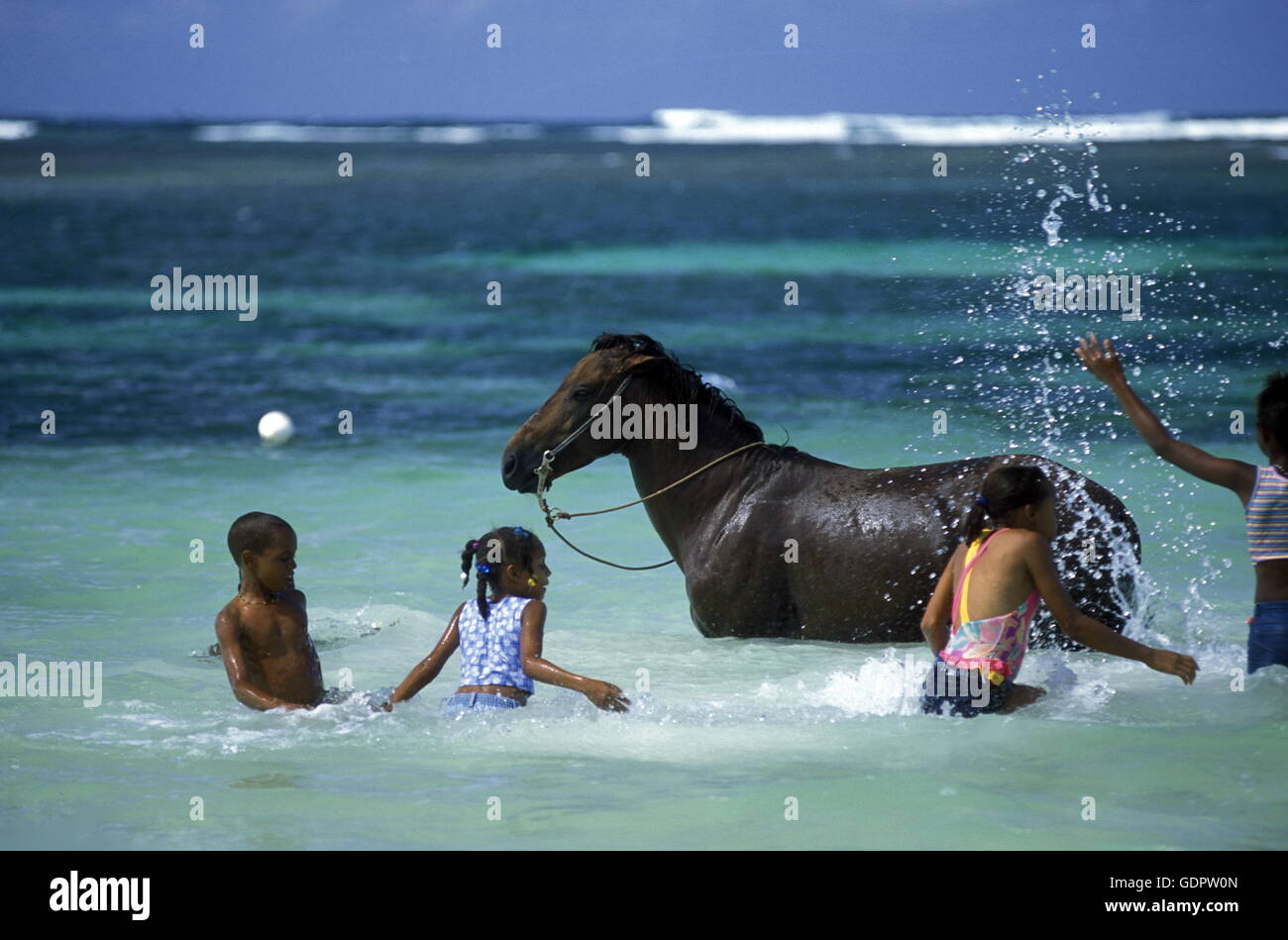 I bambini giocano con un cavallo in spiaggia presso il villaggio di Las Terrenas su Samanaon nella Repubblica Dominicana nei Caraibi se Foto Stock