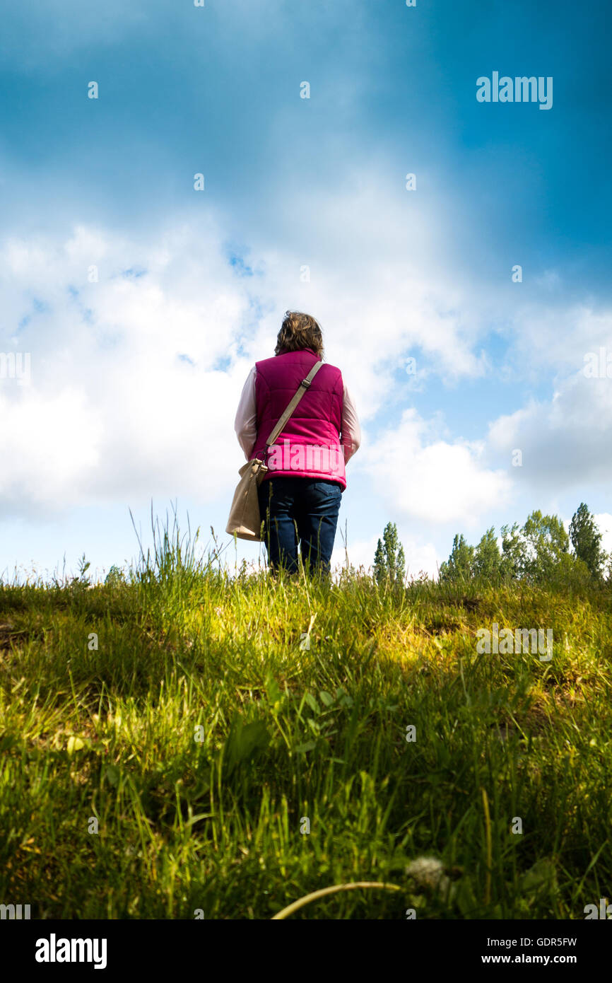 Donna in piedi sul bordo di una collina e guardare avanti Foto Stock