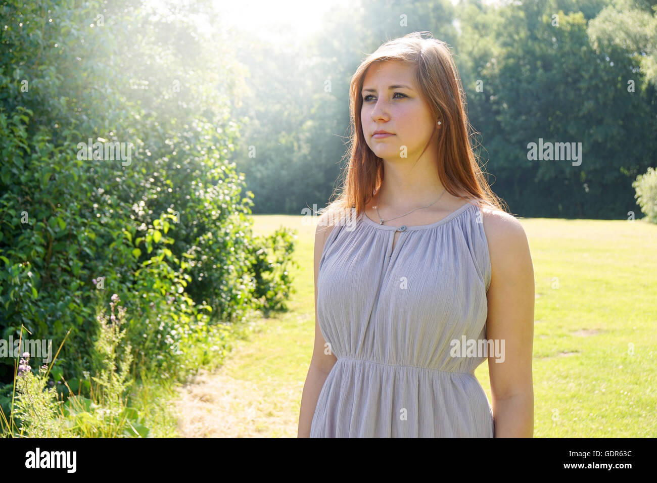 Giovane donna in un parco con sun flare Foto Stock