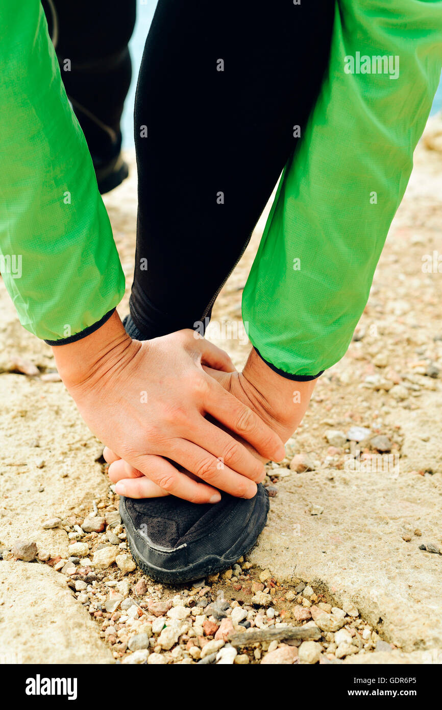 Primo piano di un giovane sportivo caucasica indossando indumenti sportivi stretching le sue gambe prima o dopo aver eseguito all'aperto Foto Stock