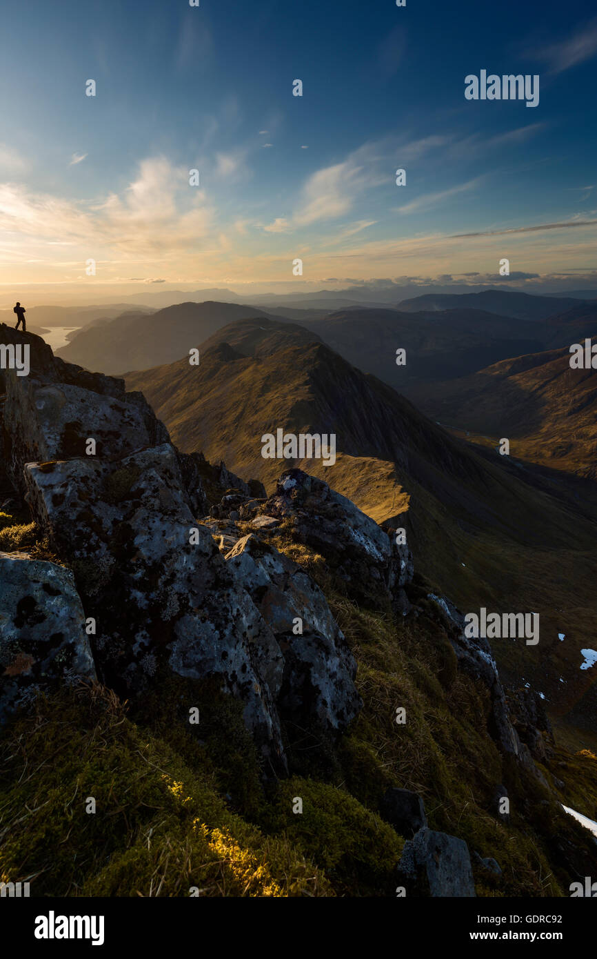 Un fotografo di paesaggio sulle ripide pendici di Sgurr Fhuaran che cattura Sgurr nan Saighead e il vasto paesaggio di Kintail al tramonto Foto Stock