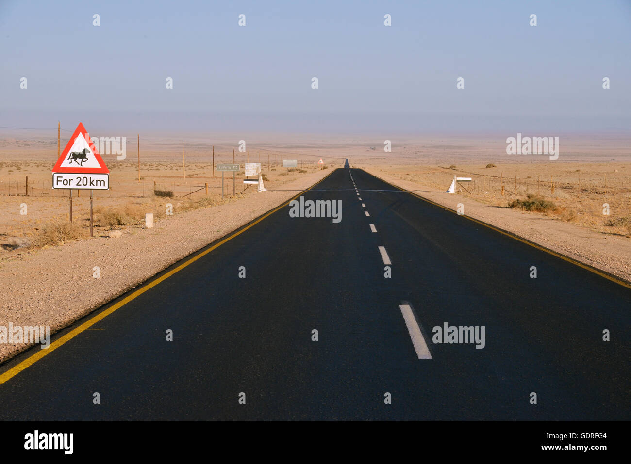 La strada attraverso il deserto con un cartello di avvertimento attenzione cavalli, vicino Aus, Karas Regione, Namib, Namibia Foto Stock