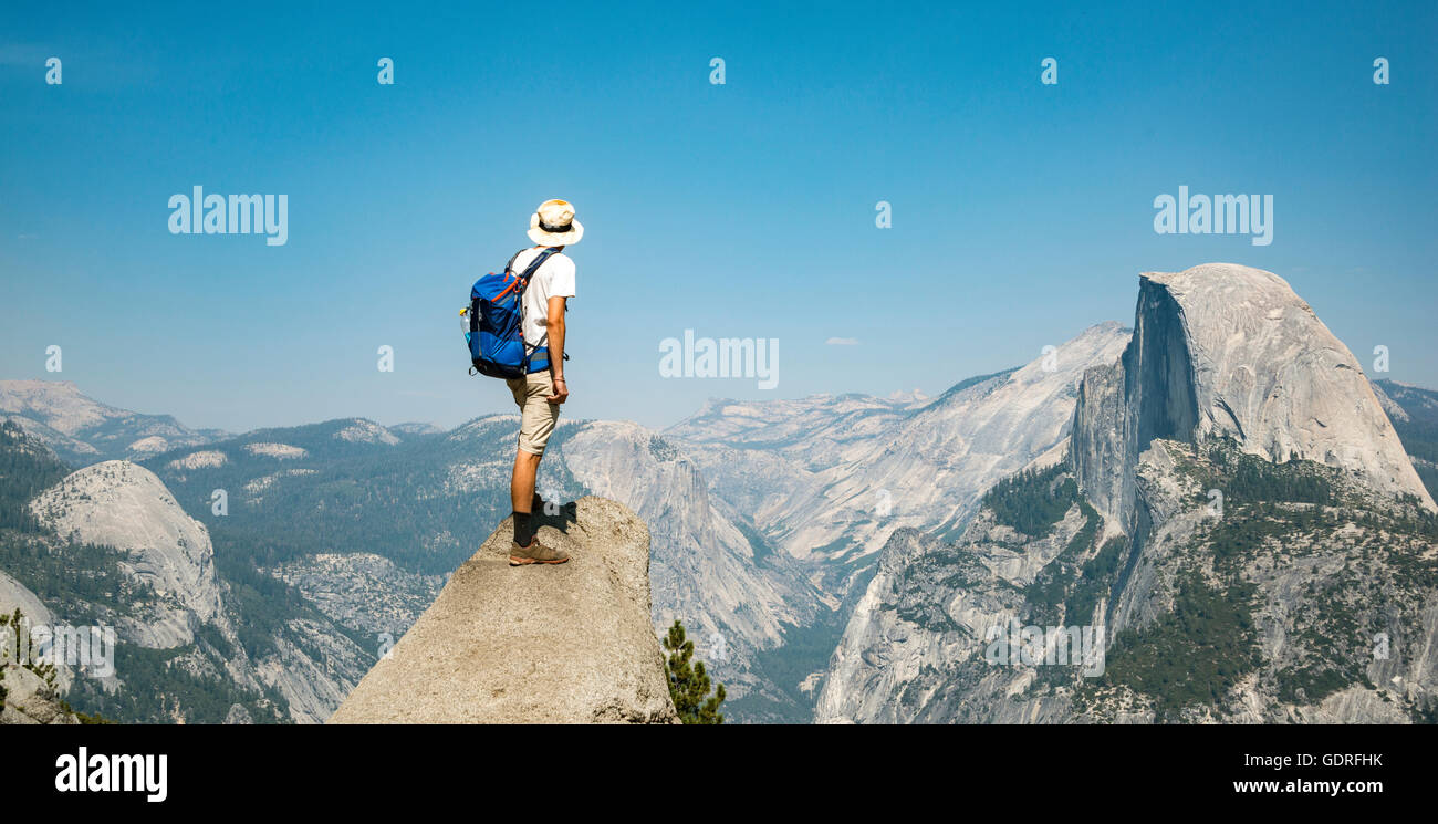 Giovane uomo in piedi sulla mensola, guardando l'Half Dome, vista dal punto ghiacciaio, Yosemite National Park, California, Stati Uniti d'America Foto Stock