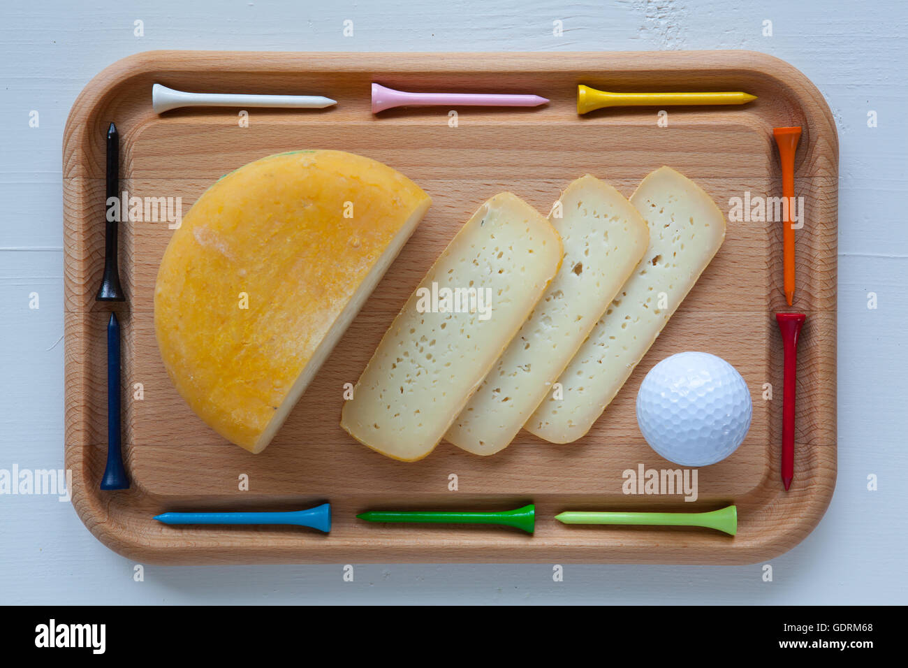 Blocco di gustosi formaggi sul tagliere con un coltello e golf tees, isolato su bianco scrivania in legno Foto Stock
