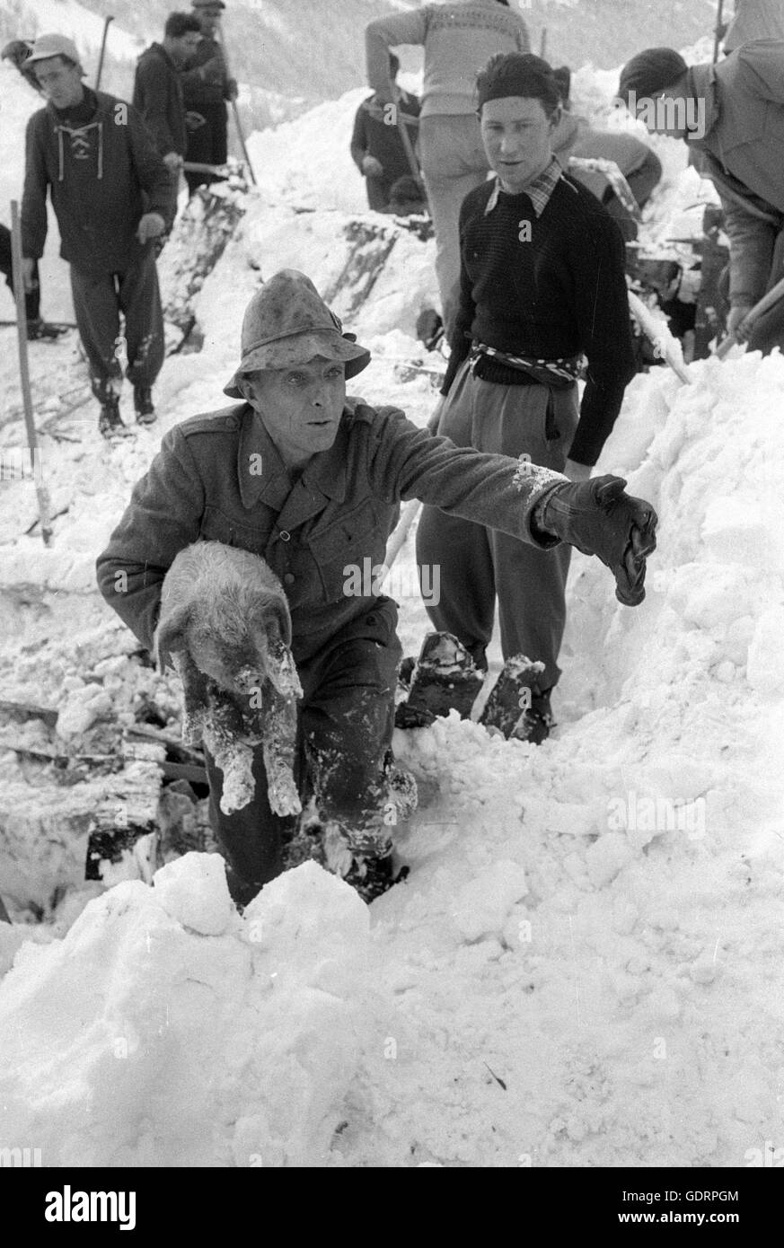 Dopo una valanga di soccorritori scavare la loro strada attraverso la neve per un edificio, 1956 Foto Stock